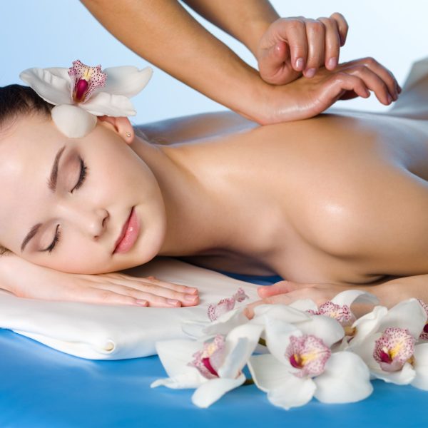 Relaxing massage of back for young beautiful woman in spa salon - horizontal